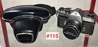 Camera with attached lens alongside black protective hard case with chrome latch