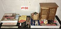 Wide view of entire lot showing cabinet, sewing basket, scissors, pins, sewing kits, and accessories on a table.