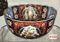 Photo of large Chinese pottery bowl showing exterior panels with floral and feather designs on red and blue backgrounds.