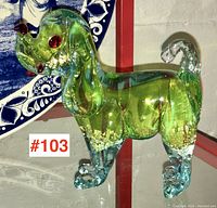 Front side view of Murano glass dog figurine showing green glass body with gold flecks and red glass nose and eyes.