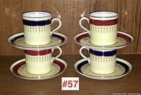 Four Aynsley demi-tasse cups and saucers; two cups and saucers with red bands, two with blue bands, all with gold detailing on cream porcelain.