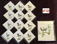 Thirteen pieces total, twelve napkins and one tablecloth, all silk embroidered with bird designs.