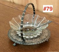 Photo of Victorian serving dish with clear blown glass bowl in silver plated caddy, floral etched glass underplate, and decorative silver plated spoon on wood surface.