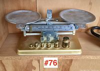 Front view of vintage Pelouze balance scale with brass weights on wooden shelf