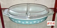 Front view of the vintage Pyrex blue divided serving dish with white snowflake pattern and clear lid with divider.
