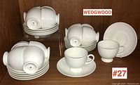 Front view of Wedgwood teacups and saucers stacked and displayed, showing the clean white design and quantity.