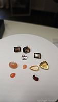 Photo of 10 loose gemstones in various shapes and colors displayed on white background.