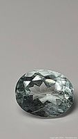 Top-down view of oval cut aquamarine gemstone showing facets and color.