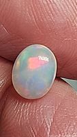 Close-up of the oval Ethiopian opal showing translucent body and bright color flashes under light.
