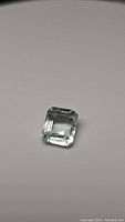 Clear close-up of 2.71 carat octagon cut aquamarine gemstone showing facets and light color against neutral background.
