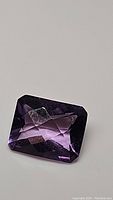 Photo of a deep purple, cushion cut amethyst with checkerboard faceting.