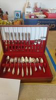 Full set of 46 Community Plate flatware displayed in wooden case with red interior lining, showing all utensils organized in slots.