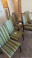 Six mid-century modern dining chairs arranged in a row, 2 with arms and 4 without, upholstered in green striped fabric.
