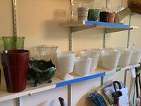 Shelf with seven glass vases including white milk glass hobnail and thumbprint pattern vases, some in footed style, along with a couple of other colored glass planters.