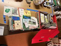 Box of mostly used golf scorecards, maps, and golf towels laid out on a table