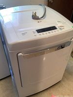 Front view of white LG electric dryer with control panel and power cord on top.