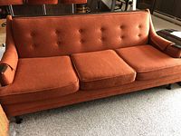 Front view of entire sofa showing overall form, upholstery color, tufted back and leg style