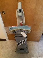 Full front view of Oreck XL upright vacuum with vacuum bags and informational papers attached to handle.