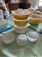 Stacked Pyrex lidded casserole dishes in yellow and white with matching starburst patterns.