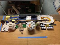 Wide view of entire lot with golf clubs, golf balls in bowl, golf gloves, towels, and notes displayed on table.
