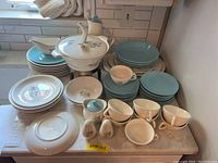 Full view of the entire collection showing plates, bowls, cups, saucers, serving bowl, gravy boat and salt/pepper shakers arranged on countertop.