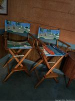 Two tall wooden director-style chairs with golf-themed replacement canvases showing golf course scenes. View shows overall condition and measurements.