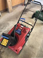 Full view of red Toro Power Clear 621 ZE snow blower with black handle, control lever, and blue electric start pull grip.