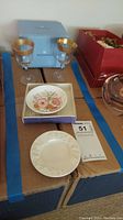 Two Wedgwood stemware glasses with gold rim, original Wedgwood box, and two small decorative dishes on cardboard surface.