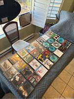 Photo of 32 assorted used music CDs laid out on blue cover, showing album artwork and jewel cases.