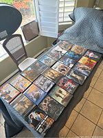 Image showing 24 DVD cases laid out on a table with visible covers of movies in various genres.