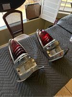 Pair of classic car tail lights with red and clear lenses, chrome trim, and mounting hardware on a quilted moving blanket.