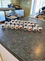Front angled view showing 26 mini mugs with different NHL team logos arranged in rows on a kitchen counter.