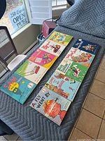 Photo showing ten Dr. Seuss beginner books laid out on a covered surface, titles include 'Sam and the Firefly', 'A Fly Went By', 'Come Over to My House', among others.