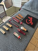 Overview of 11 assorted draft beer handles and a black Stoli bar mat with red logo on a gray quilted blanket.