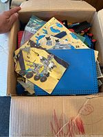 Open cardboard box showing vintage LEGO instruction booklets on top with assorted bricks inside