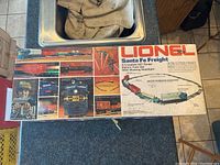 Box lying on countertop showing colorful product graphics and Lionel logo, details Santa Fe Freight electric train set and track layout illustration.