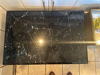 Top view of the rectangular black marble tabletop with white veining and polished finish.