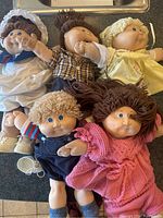 Five original Cabbage Patch dolls laid out, showing full bodies and clothing variations.