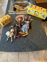 Three puppets with two original decorative boxes on countertop, showcasing size and colors.