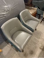 Front and side view of 2 gray swivel chairs with patterned exterior sides.