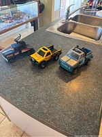 Three Tonka trucks displayed on counter showing variety and size comparison.