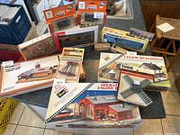 Full lot overview showing multiple boxed train buildings and accessories for HO scale including Tyco and Revell brand kits.