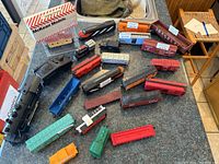 Overview of assorted model train engines and cars of varying sizes and colors spread on countertop.