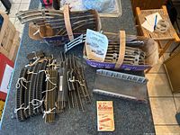 Top-down photo of various HO scale curved and straight train track sections tied in bundles in a cardboard box alongside a metal item and an instruction card.