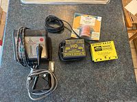 Top down image showing all items in the lot, including the Trainmaster transformer, HO Power Pack, yellow Lionel controller, solder wire, and additional control box.