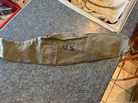 Green canvas US Military gun slip laid flat on countertop with visible U.S. markings and military stamps.