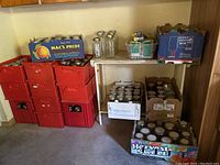 Multiple red plastic crates stacked with clear glass jars, Mac’s Pride and Harvest Sweet cardboard trays on top containing jars and lids.