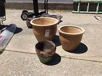 Full view of the three ceramic planters outside on a paved surface showing size and color details