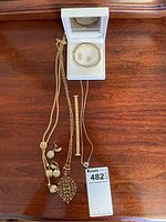 Top view of costume jewelry including multiple necklaces, bracelets, and earrings laid out on a wooden surface and in a display box