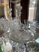 Crystal decanters with stoppers and various crystal glasses arranged in a cabinet, showing detailed cut crystal designs.